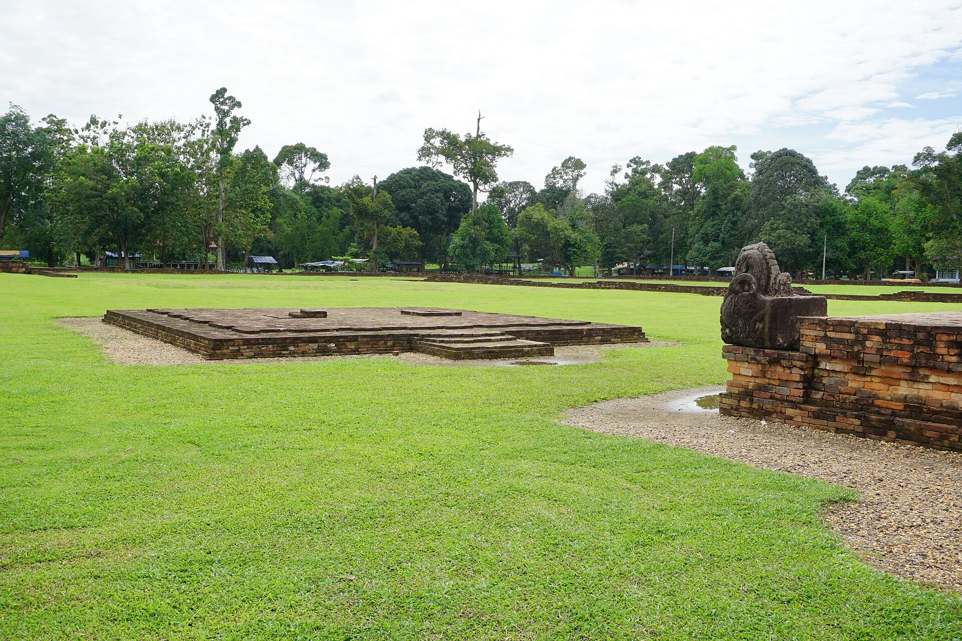 Structure en brique de Candi Gumpung parmi l’herbe et les arbres de Muara Jambi.