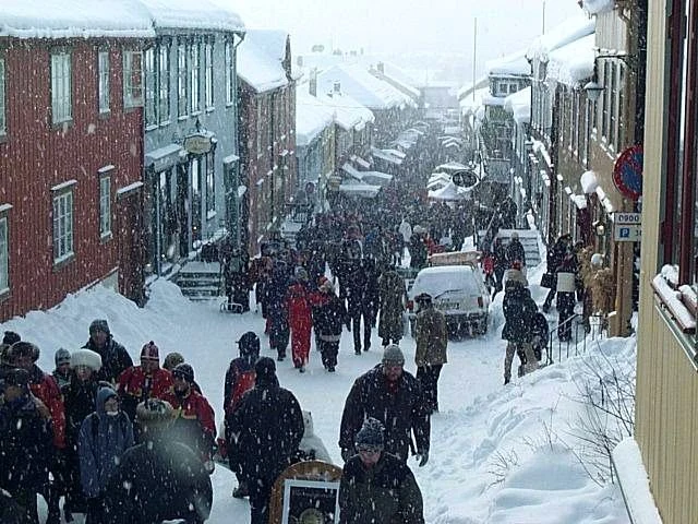 Case in legno scuro lungo una strada innevata nel centro storico di Røros.