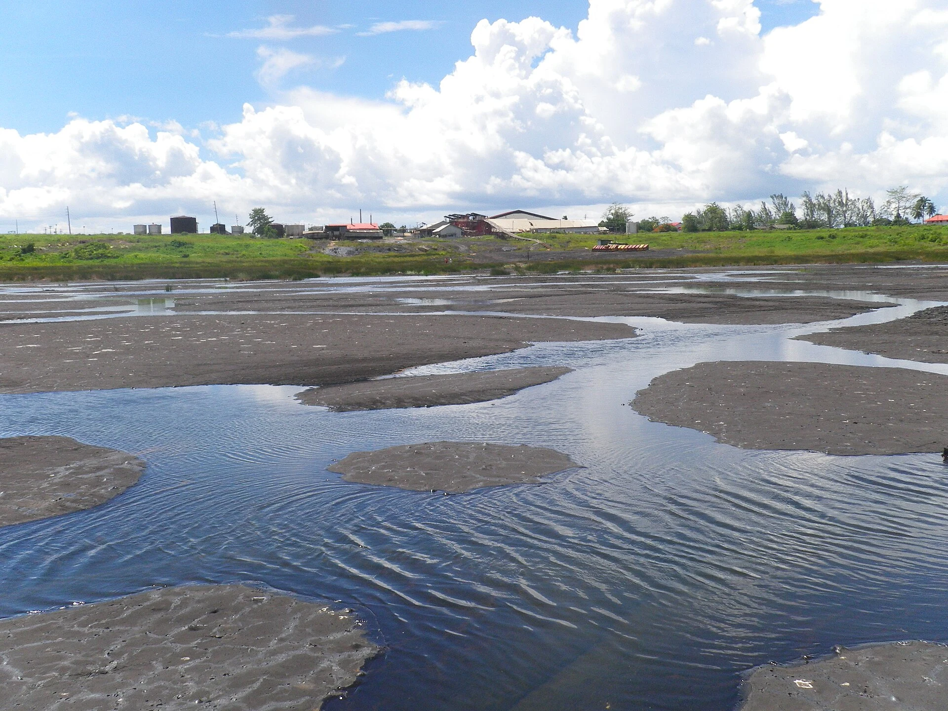 Natürliche Asphaltfläche mit Rissen und Wasser am Pitch Lake in La Brea
