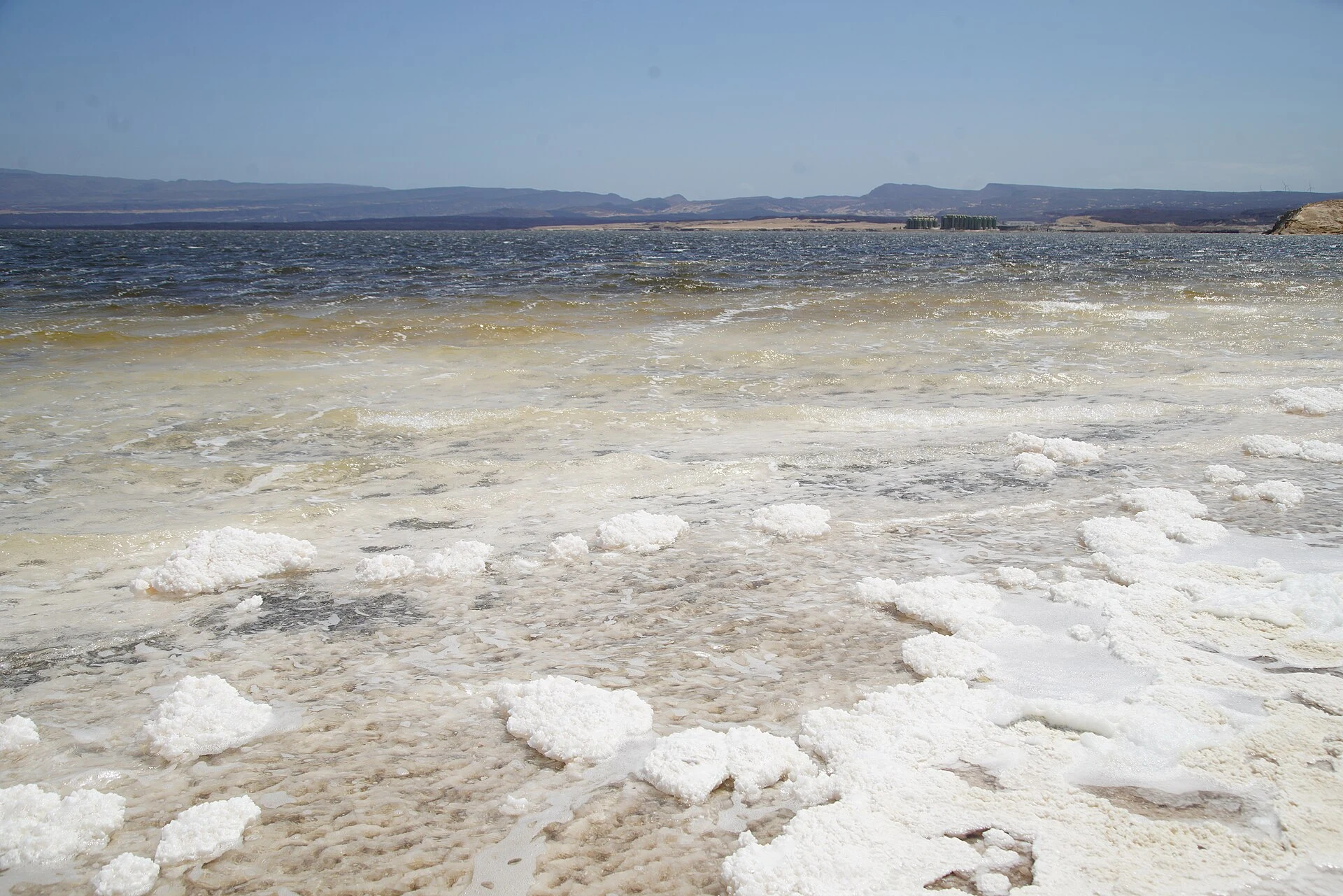 Veduta ampia del Lago Assal con croste di sale, acqua turchese e rilievi vulcanici.