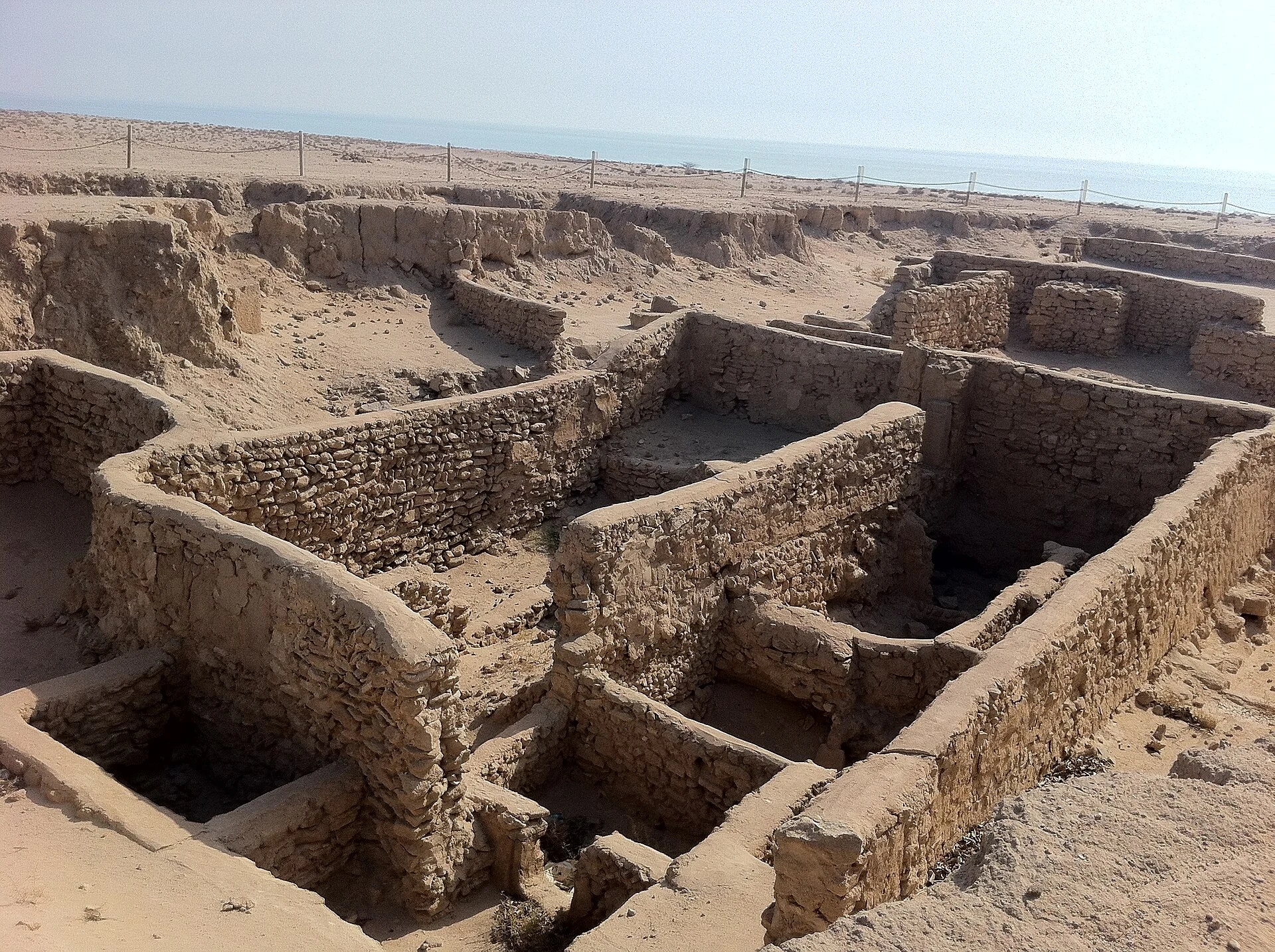 Chemin de terre et ruines discrètes dans le paysage culturel de Failaka.