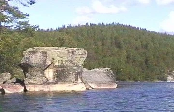 Paddler mit Schwimmweste an den Felsen von Kolovesi.