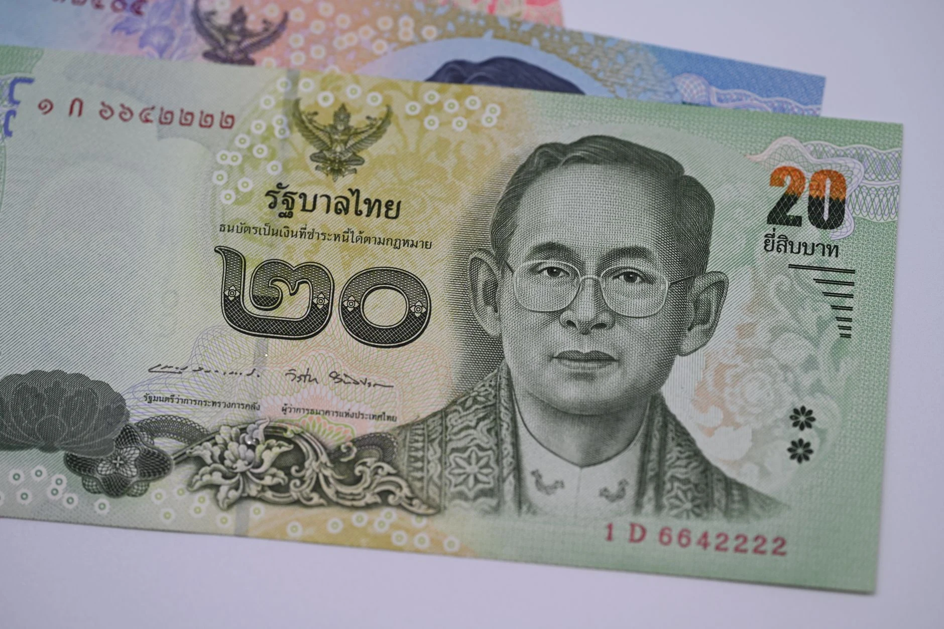 Banconote di baht thailandese accanto a testo in lingua thai come riferimenti nazionali.