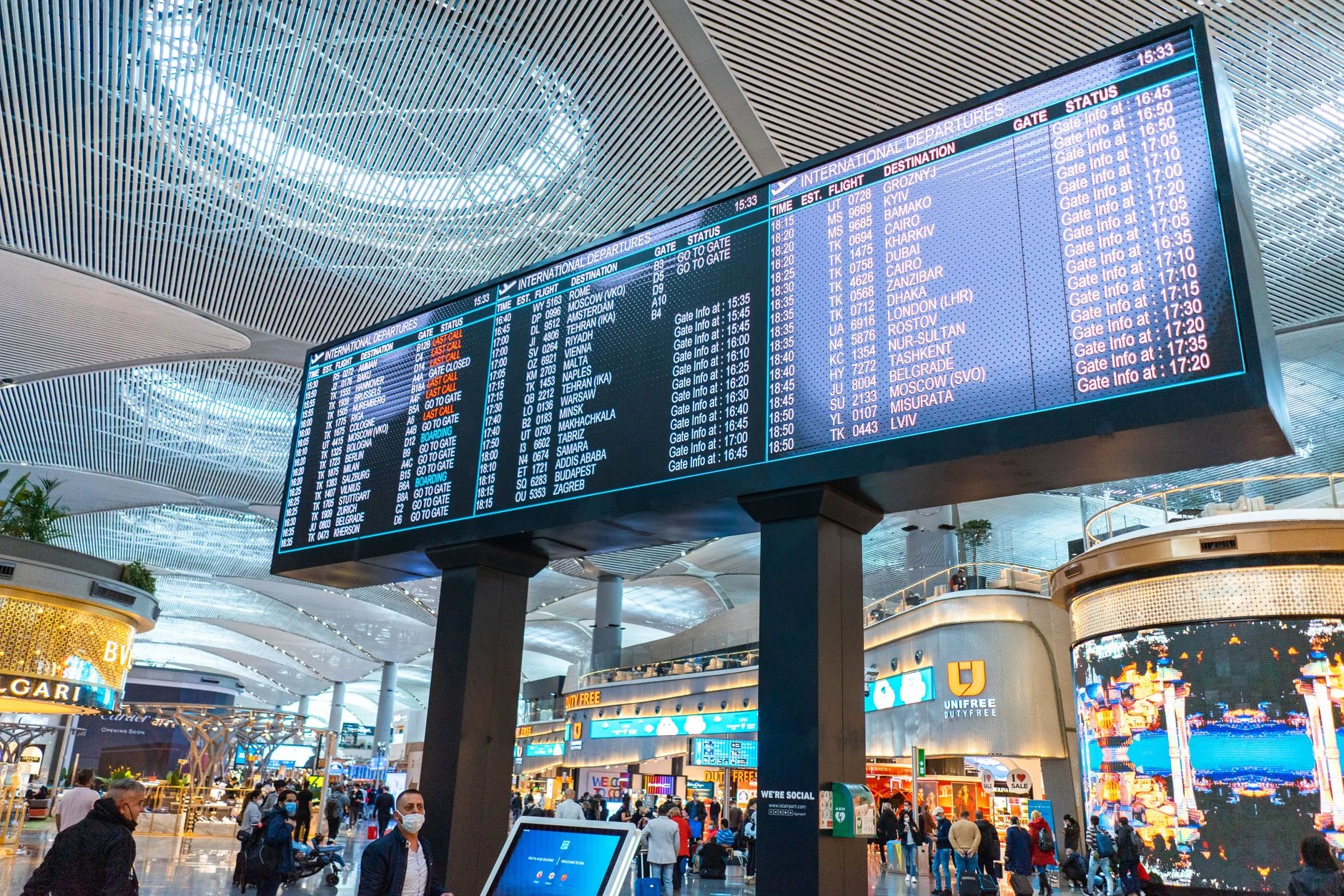 Uma pessoa consulta informações de voos num aeroporto; os horários não estão legíveis.